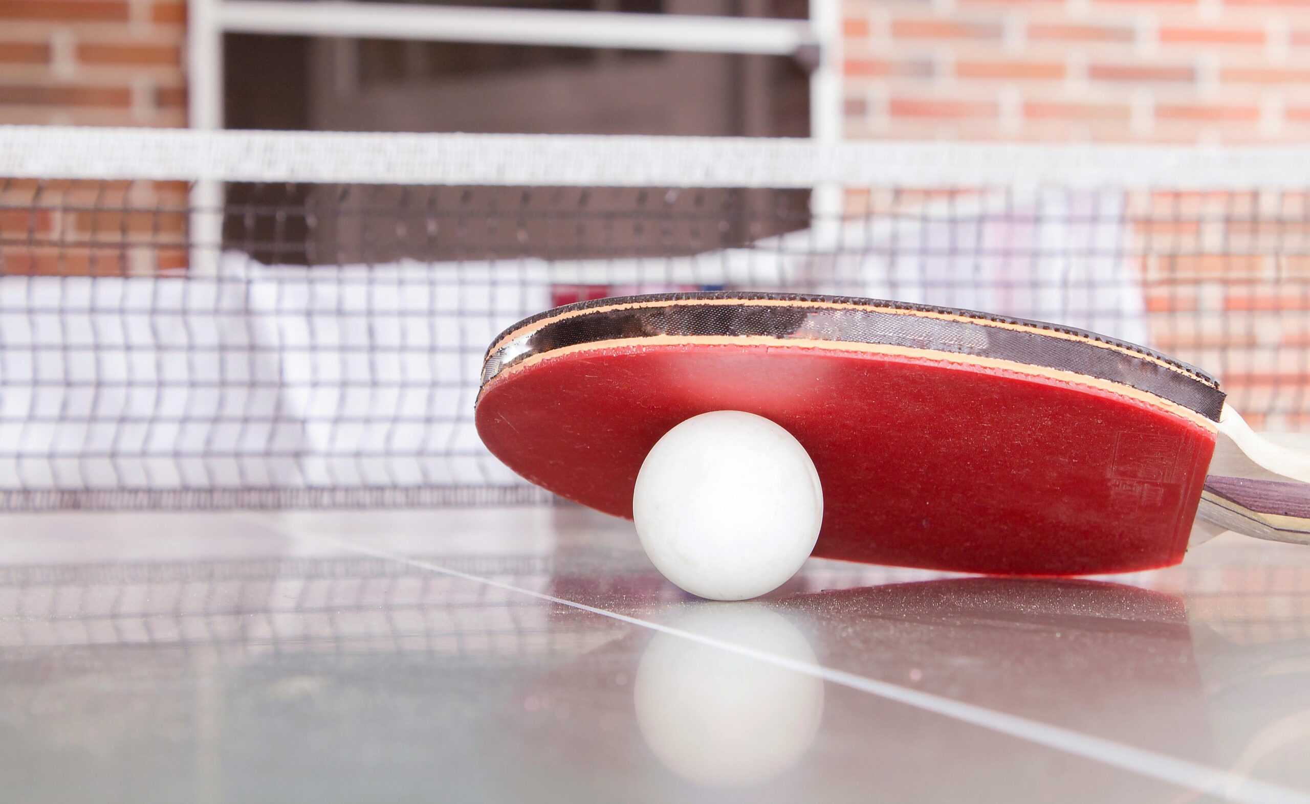 Close-up shot of a table tennis paddle and ball on a table, capturing the essence of the sport.
